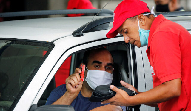 A man wearing a protective face mask pays at a gas station after Venezuela's government launched new fuel pricing system, in Caracas, Venezuela June 1, 2020. REUTERS/Manaure Quintero