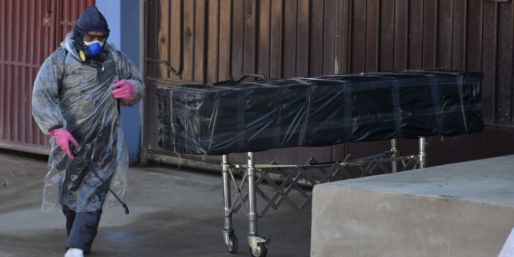 Empleados de una funeraria retiran el cuerpo sin vida de un hombre que permaneció durante horas abandonado en una calle, este domingo en Cochabamba (Bolivia). EFE/Jorge Ábrego