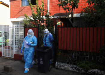 Foto de la médica venezolana Norelis Portal (D) y la técnica en enfermería chilena Blanca Pimente abandonando la casa de un paciente con coronavirus en Santiago. 
Jul 2, 2020. REUTERS/Pablo Sanhueza