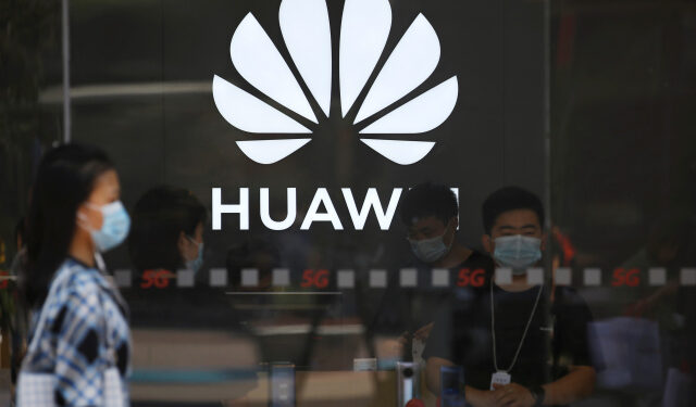 A woman wearing a face mask following the coronavirus disease (COVID-19) outbreak walks past a Huawei store at a shopping complex in Beijing, China July 14, 2020. REUTERS/Tingshu Wang