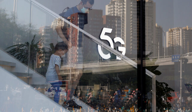 A man and a child wearing face masks following the coronavirus disease (COVID-19) outbreak walk past a 5G sign inside a Huawei store at a shopping mall in Beijing, China July 14, 2020.  REUTERS/Tingshu Wang