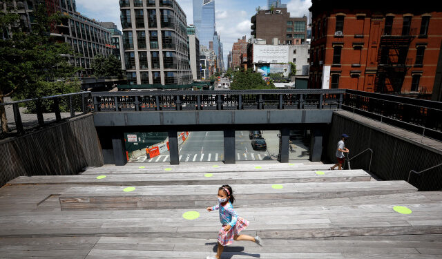 A child wearing a protective face mask plays on a sitting platform painted with social distancing circles on the elevated High Line Park in Manhattan on the first day of the park's re-opening following the outbreak of the coronavirus disease (COVID-19) in New York City, New York, U.S., July 16, 2020. REUTERS/Mike Segar     TPX IMAGES OF THE DAY