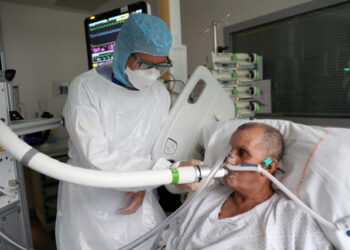 Christian George, director de investigación del Centro Nacional de Investigación Científica, ayuda a un paciente que sufre de COVID-19, la enfermedad causada por el coronavirus, a usar la máquina que examina el aliento en el Hospital La Croix-Rousse en Lyon, Francia. 22 de julio, 2020. REUTERS/Yiming Woo