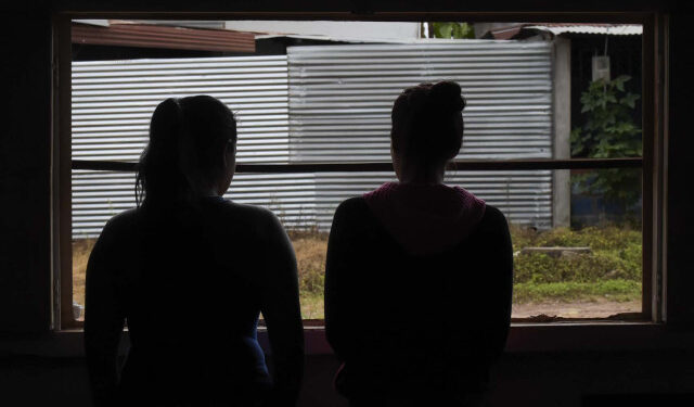 Venezuelan sex workers Joli (L), 35, and her niece Milagro, 19, look through a window during an interview with AFP at a bar in Calamar municipality, Guaviare department, Colombia on October 11, 2018. - Venezuelan migrants who fled their country due to the crisis, turn to prostitution in Colombia for the lack of opportunities to work in other trades. (Photo by Raul ARBOLEDA / AFP)