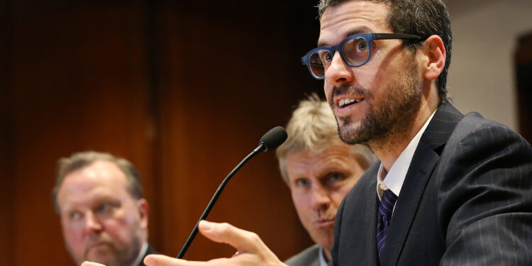 BOSTON MA. - MARCH 4:  Dr. Paul Biddinger, Vice Chair for Emergency Preparedness in the Dept. of Emergency Medicine at MGH and  Dr. Davidson Hamer, BU Professor of Global Health and Medicine, listen as  Dr. Michael Mina, Assistant Professor of Epidemiology and Assistant Professor in Immunology and Infectious Diseases at Harvard, speak before the Joint Committee on Public Health hearing to address the stateÕs continued preparedness for the coronavirus on March 4, 2020 in Boston, MA. (Staff Photo By Nancy Lane/MediaNews Group/Boston Herald)