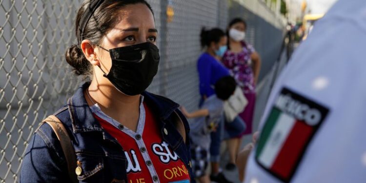 Imagen de archivo. Una migrante habla con un agente de inmigración afuera de las instalaciones del Instituto Nacional de Migración (INM), mientras espera renovar su permiso para permanecer legalmente en México para aguardar su audiencia en Estados Unidos. Ciudad Juárez, México. 8 de julio de 2020. REUTERS / José Luis González