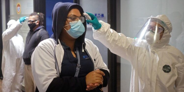 Workers of a truck part factory get their temperature checked as they prepare to resume activities after it was closed for several weeks to prevent the spread of coronavirus in San Luis Potosi, Mexico on May 27, 2020. (Photo by MAURICIO PALOS / AFP)