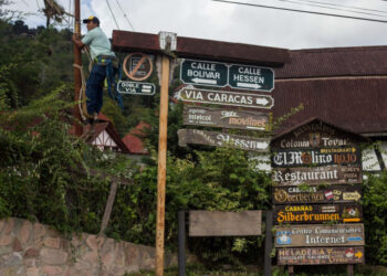 A worker climbs a pole in Colonia Tovar, Tovar Municipality, Aragua state, Venezuela, on November 13, 2020. - Colonia Tovar (Aragua state, center), a town of 21,000 inhabitants famous among Venezuelans for its traditional Bavarian style houses with reddish gabled roofs, lives off tourism and agriculture. The first activity  halted due to the coronavirus, with a quarantine that prevented for months that visitors arrived, and the second was hit by the shortage of fuel that paradoxically punishes this country, once an oil power. (Photo by Cristian Hernandez / AFP)