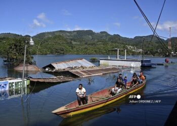 Residents travel on a boat in a flooded street in Comunidad Campur indigenous community, Guatemala, on December 10, 2020. - The indigenous community of Campur in northern Guatemala has become a lagoon after the passage of hurricanes Eta and Iota, which left 160 dead and disappeared in the country. (Photo by Johan ORDONEZ / AFP)