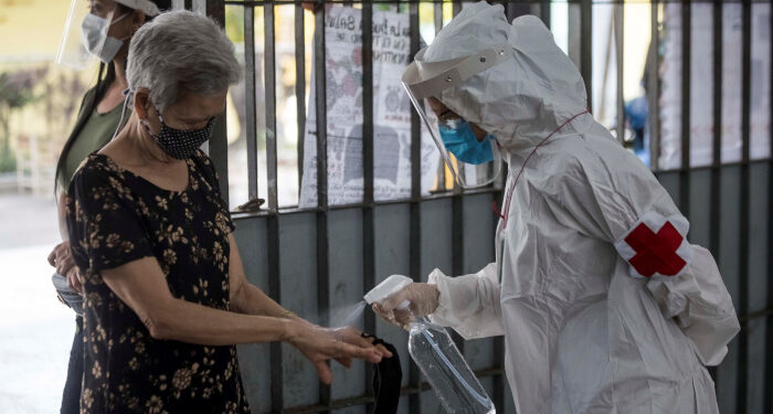 Personal sanitario rocía líquido desinfectante a una mujer. EFE/ Miguel Gutiérrez/Archivo