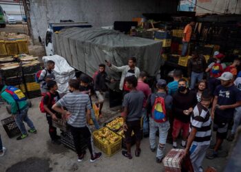 VENEZUELA ECONOMÍA***AME560. CARACAS (VENEZUELA), 21/01/2021.- Personas que se dedican a obtener productos mediante trueque con plátanos trabajan en un galpón ubicado en Catia, el 18 de enero de 2021 en Caracas (Venezuela). Como si de un deporte extremo se tratase, Bryan, Samuel y Alexandra caminan las empinadas calles del barrio caraqueño de Catia con una cesta a cuestas cargada con plátanos. El objetivo: intercambiarlos por productos que luego venderán para poder sobrevivir en medio de la severa crisis económica venezolana. El trueque del siglo XXI. EFE/RAYNER PEÑA R