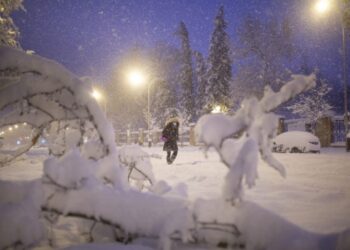 A woman walks amid a heavy snowfall in Madrid on January 9, 2021. - Heavy snow fell across much of Spain, leaving huge areas blanketed in white as Storm Filomena brought wintry weather not seen in decades to the Iberian peninsula. (Photo by Benjamin Cremel / AFP)