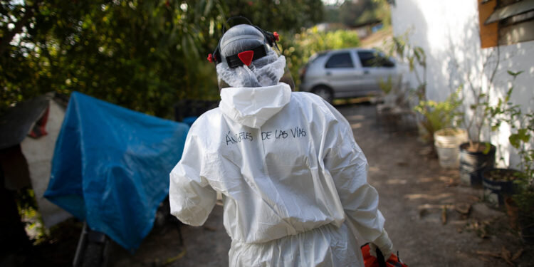 Wearing a biosecurity suit, Dr. Debora Mejia, an Angels of the Road volunteer, walks out of a house after visiting two COVID-19 patients in Caracas, Venezuela, Wednesday, Feb. 3, 2021. Each day brings on average three to four calls, and the new coronavirus pandemic means that at least one of those is a request to take a patient with trouble breathing to a hospital. (AP Photo/Ariana Cubillos)