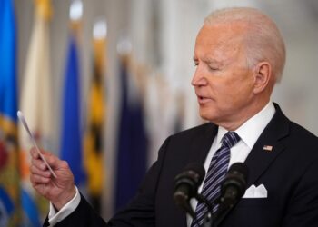 US President Joe Biden looks at a card he pulled from his pocket to read the number of Americans who have died of Covid-19 to date, as he speaks on the anniversary of the start of the Covid-19 pandemic, in the East Room of the White House in Washington, DC on March 11, 2021. (Photo by MANDEL NGAN / AFP)