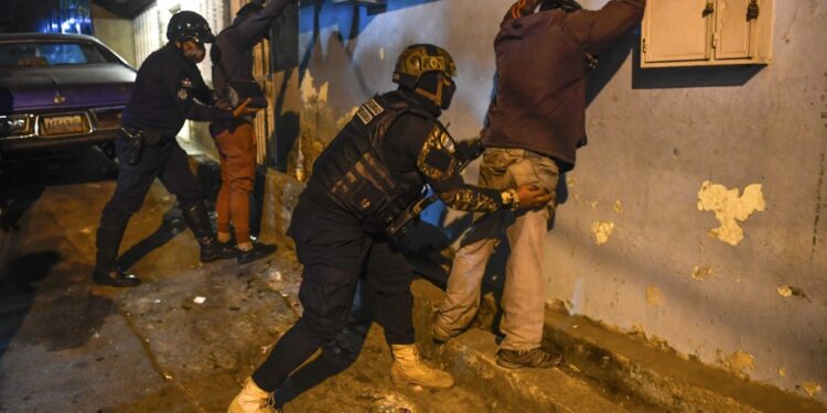 Members of the Venezuelan Scientific Police (CICPC) frisk men during an operation amid the COVID-19 pandemic in Los Teques, Miranda state, Venezuela, on March 20, 2021. - In Miranda there is a circulation restriction since 18h00, there is the order to close stores at 16h00, to wear face masks and to prevent meetings of more than five people, amid a second wave of the COVID-19 pandemic. (Photo by Federico PARRA / AFP)