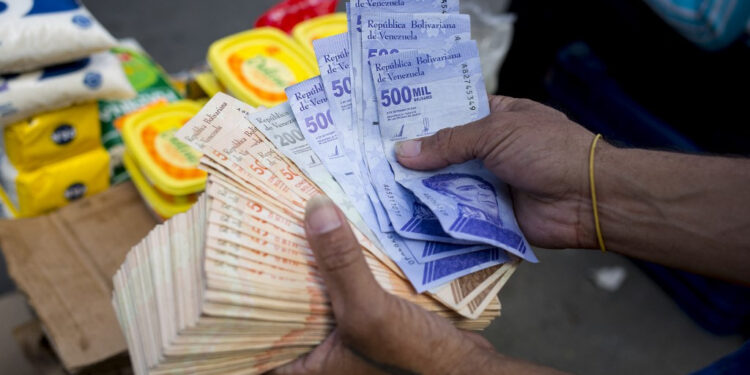 A man holds Bolivar bills a street market in Caracas' Catia neighborhood, on April 6, 2021, amid the Covid-19 pandemic. (Photo by Pedro Rances Mattey / AFP)