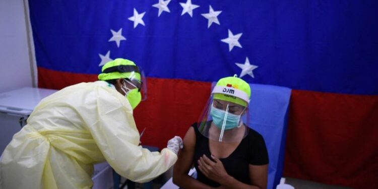 A health worker administers a dose of the Sputnik V vaccine against COVID-19 to a staff member of the Perez de Leon Hospital in Petare neighbourhood, in eastern Caracas, on February 19, 2021, amid the novel coronavirus pandemic. (Photo by Federico PARRA / AFP)