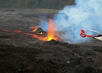 This photograph taken on April 10, 2021, shows a helicopter flying as lava is erupting from Piton de la Fournaise volcano, on the southern side of the volcano, on the French Indian Ocean island of Reunion. / AFP / Richard BOUHET