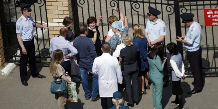 People gather by the fence of School No. 175 following a shooting in Kazan on May 11, 2021. (Photo by Roman Kruchinin / AFP)