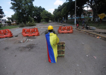 Manifestante de primera línea envuelto en bandera de Colombia en barricada, Cali, Colombia, 13 mayo 2021.
REUTERS/Luisa González