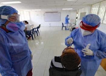 A health worker takes a swab sample for a COVID-19 coronavirus test from a Venezuelan woman in Cucuta, on the Colombian border with Venezuela, on December 28, 2020. - Colombia has been one of the worst hit countries in Latin America by the pandemic with more than 1.5 million cases and over 40,000 deaths. (Photo by Schneyder MENDOZA / AFP)