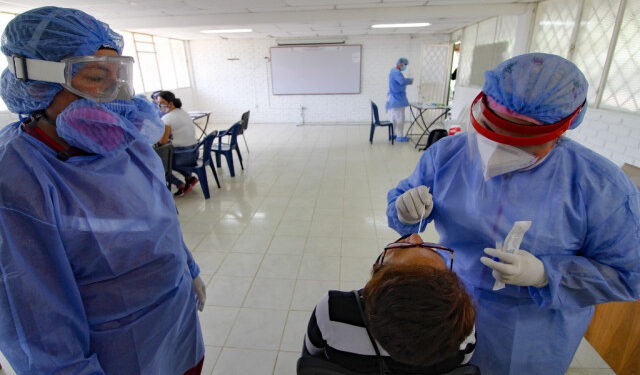 A health worker takes a swab sample for a COVID-19 coronavirus test from a Venezuelan woman in Cucuta, on the Colombian border with Venezuela, on December 28, 2020. - Colombia has been one of the worst hit countries in Latin America by the pandemic with more than 1.5 million cases and over 40,000 deaths. (Photo by Schneyder MENDOZA / AFP)