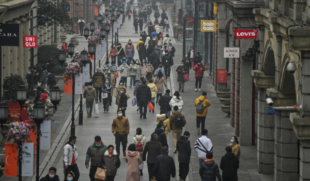 People walk along a pedestrian street in Wuhan, China's central Hubei province on January 23, 2021, one year after the city went into lockdown to curb the spread of the Covid-19 coronavirus. (Photo by Hector RETAMAL / AFP)