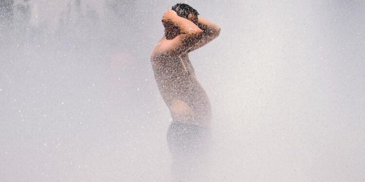 A man cools off in the Salmon Street springs fountain in Portland, Oregon on June 28, 2021, as a heatwave moves over much of the United States. - Swathes of the United States and Canada endured record-setting heat on June 27, 2021, forcing schools and Covid-19 testing centers to close and the postponement of an Olympic athletics qualifying event, with forecasters warning of worse to come. The village of Lytton in British Columbia broke the record for Canada's all-time high, with a temperature of 46.6 degrees Celsius (116 Fahrenheit), said Environment Canada. (Photo by Kathryn Elsesser / AFP)