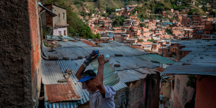 ACOMPAÑA CRÓNICA VENEZUELA AGUA***AME7356. CARACAS (VENEZUELA), 23/02/2021.-Fotografía del 11 de febrero del 2021 donde se observa a un hombre cargar una botella de 25 litros de agua, en Caracas (Venezuela). El experto en políticas públicas y director de la ONG local Ojo Avizor, Norberto Baussón, advierte a Efe que la falla en el suministro de agua corriente afecta, en el mejor de los casos, a casi 9 de cada 10 hogares del país. "El porcentaje por región varía entre un 87 % y un 99 % de afectación por falta de agua. Eso lo que quiere decir es que es un problema nacional, no un problema asociado a una región o alguna circunstancia", señala. EFE/ Miguel Gutiérrez