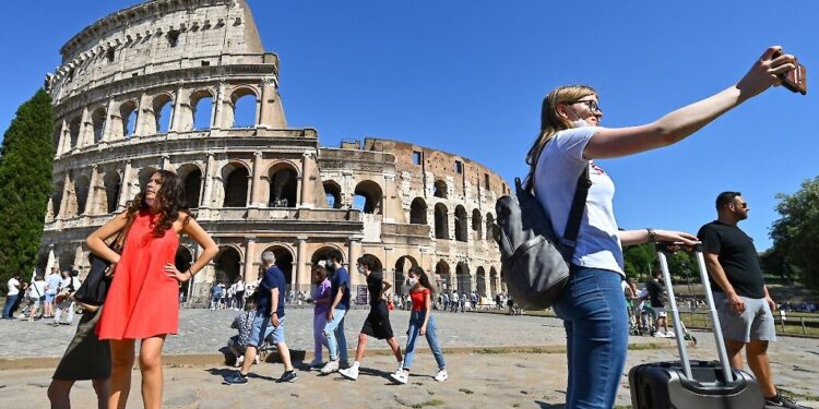 A woman takes a selfie in front of Rome's landmark Colosseum on June 12, 2021 as six more of Italy's regions and autonomous provinces will be allowed to drop most remaining Covid-19 health measures from June 14 as the latest data showed infection rates remain low nationwide. (Photo by Alberto PIZZOLI / AFP)