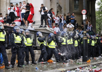 A line of police officers are the target of beer can throwers as England supporters stand around the edges of Trafalgar Square during a live screening of the UEFA EURO 2020 final football match between England and Italy in central London on July 11, 2021. (Photo by Tolga Akmen / AFP)