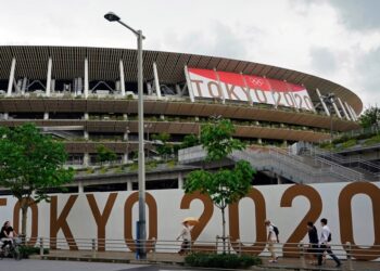 Tokyo (Japan), 23/06/2021.- (FILE) - Passersby walk past the National Stadium, the main stadium of the 2020 Tokyo Olympic Games, in Tokyo, Japan, 23 June 2021 (reissued 17 July 2021). According to a statement from the Tokyo 2020 Organising Committee, a person staying within the Olympic Village tested positive for COVID-19, and was subsequently placed in 14 day quarentine. (JapÛn, Tokio) EFE/EPA/FRANCK ROBICHON