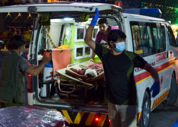 EDITORS NOTE: Graphic content / Medical staff bring an injured man to a hospital in an ambulance after two powerful explosions, which killed at least six people, outside the airport in Kabul on August 26, 2021. (Photo by Wakil KOHSAR / AFP)