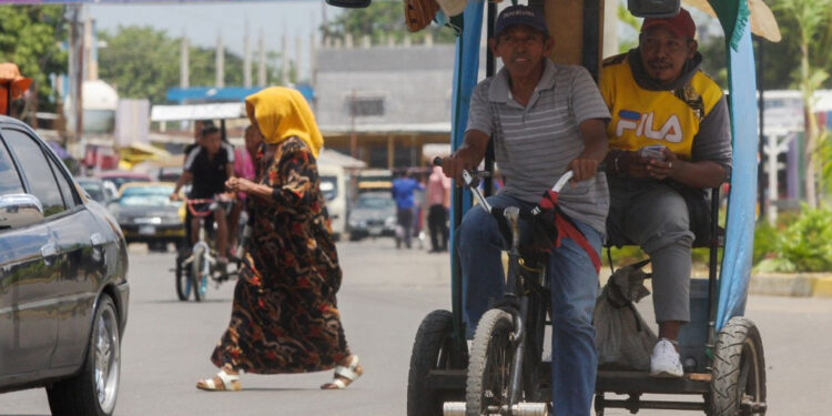 A man rides a traditional tricycle taxi in Maracaibo, Zulia State, Venezuela, on July 29, 2021. - Franklin relies on the wind to power his small sailboat. Manuel, a former bus driver, carries passengers in a "bicitaxi". Both manage to survive the chronic fuel shortages in Zulia, the region that saw the birth of Venezuela's oil industry. (Photo by Luis BRAVO / AFP)