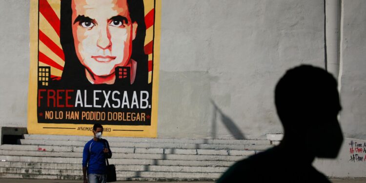 People walk past graffiti in favor of the release of Colombian businessman Alex Saab, amidst the Coronavirus pandemic, on the west side of the city in Caracas, Venezuela on September 8, 2021. (Photo by Javier Campos/NurPhoto)