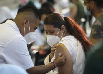 Fotografía de archivo del 24 de agosto de 2021 que muestra a un vacunador tras aplicar una dosis de la vacuna contra la covid-19 a una mujer, en Ciudad de México. La desigualdad sigue marcando el proceso de inmunización contra la covid-19 en América, donde organismos internacionales urgen por fortalecer la producción local de dosis en medio de la nueva ola de la pandemia y el debate creciente sobre la exigencia de un certificado de vacunación. EFE/ Sáshenka Gutiérrez