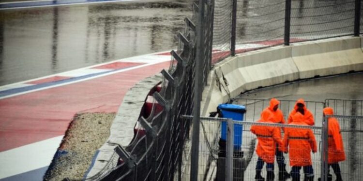 Personal del circuito de Sochi charla bajo la lluvia tras la suspensión de los terceros ensayos libres del Gran Premio de Rusia de Fórmula 1, el 25 de septiembre de 2021. Foto AFP.