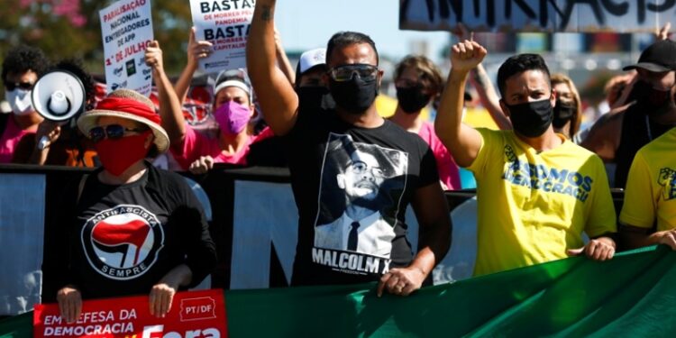 People raise their fists during a protest against Brazilian President Jair Bolsonaro and racism in Brasilia, Brazil, on June 21, 2020, amid the COVID-19 coronavirus pandemic. - The novel coronavirus has killed at least 464,423 people worldwide since the outbreak began in China last December, being Brazil Latin America's worsthit country with 49,976 deaths from 1,067,579 cases. (Photo by Sergio LIMA / AFP)