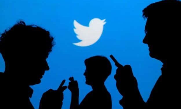 FILE PHOTO: People holding mobile phones are silhouetted against a backdrop projected with the Twitter logo in this illustration picture taken September 27, 2013. REUTERS/Kacper Pempel/Illustration/File Photo/File Photo