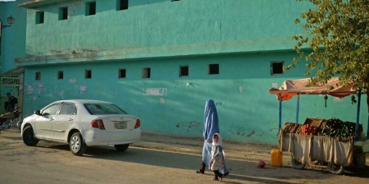 Una mujer afgana vestida con burka y una niña caminan por una calle en Qala-e-Naw, en la provincia de Badghis el 16 de octubre de 2021 Hoshang Hashimi AFP