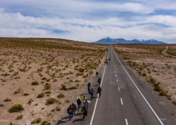 Vista aérea de migrantes venezolanos caminando por la carretera que une la ciudad fronteriza de Colchane con Iquique, Chile el 23 de septiembre de 2021. – Migrantes venezolanos que cruzan la frontera de Bolivia a Chile, buscan refugio en el desierto luego de cruzar cinco países sudamericanos. (Foto de MARTIN BERNETTI / AFP)