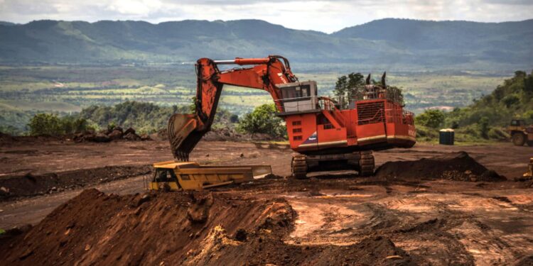 An excavator moves earth to a dump truck on the open mining site of Venezuelan iron ore producer, CVG Ferrominera Orinoco, on Bolivar Hill outside of Ciudad Piar, Venezuela, on Thursday, July 9, 2015. Photographer: Meridith Kohut/Bloomberg