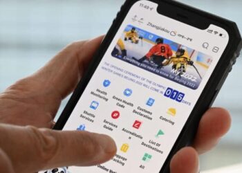 A user holds a mobile phone showing the Winter Olympic Games 2022 official app "MY 2022" in Beijing on January 20, 2022. (Photo by François-Xavier MARIT / AFP) (Photo by FRANCOIS-XAVIER MARIT/AFP via Getty Images)