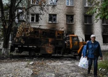 Dos mujeres pasan por delante de una residencia destruida en Balakliya, región de Kharkiv, el 17 de septiembre de 2022, en medio de la invasión rusa de Ucrania. (Foto de Juan BARRETO / AFP)