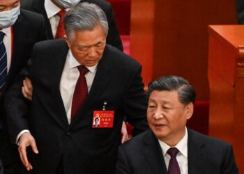 China's President Xi Jinping (R) talks to former president Hu Jintao as he is assisted to leave from the closing ceremony of the 20th Chinese Communist Party's Congress at the Great Hall of the People in Beijing on October 22, 2022. (Photo by Noel CELIS / AFP)