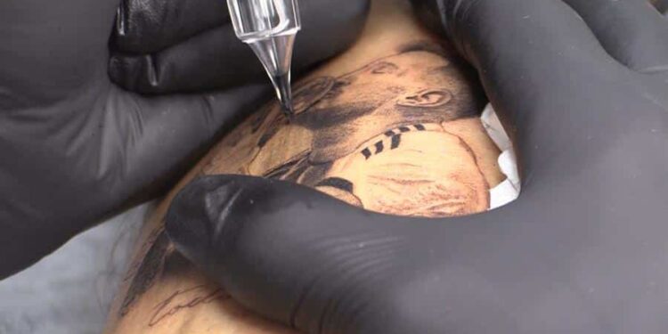 Una persona se hace un tatuaje de Lionel Messi besando la Copa del Mundo, el 20 de diciembre de 2022 en Rosario (Argentina). El furor por Messi no tiene límite. Menos aún en Rosario, la ciudad que lo vio nacer, donde algunos de los principales salones de tatuaje no dan abasto para atender las solicitudes recibidas para inmortalizar en la piel el rostro del ídolo, tras ganar Argentina el domingo pasado su tercer Mundial. EFE/ Rodrigo García