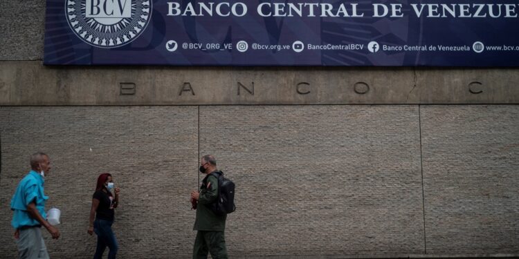 People walk in front of the main facade of the Central Bank of Venezuela in Caracas on August 25, 2022. (Photo by Yuri CORTEZ / AFP)