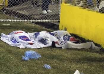 EDITORS NOTE: Graphic content / Victims' bodies are seen covered with Alianza's flags following a stampede during a football match between Alianza and FAS at Cuscatlan stadium in San Salvador, on May 20, 2023. Nine people were killed May 20, 2023 in a stampede at an El Salvador stadium where soccer fans had gathered to watch a local tournament, police said. (Photo by Milton FLORES / AFP)