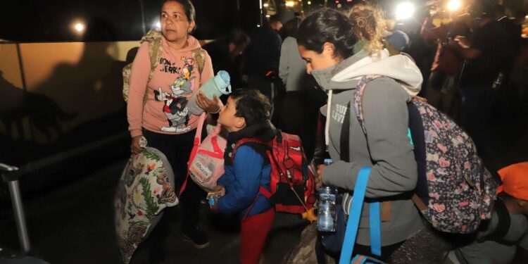 Venezuelan migrants board a bus that will take them to a shelter in the city of Arica, Chile on May 5, 2023. - A first repatriation flight for hundreds of Venezuelan migrants stranded on the border with Peru following the tightening of migration controls, will arrive in Chile early Sunday morning, Chilean Foreign Minister Alberto van Klaveren stated. The flight, sent by the Venezuelan government, will land in the city of Arica, to pick up migrants waiting on the Chilean side at the Chacalluta border crossing and another group in the Peruvian city of Tacna. (Photo by AGUSTIN MERCADO / AFP)