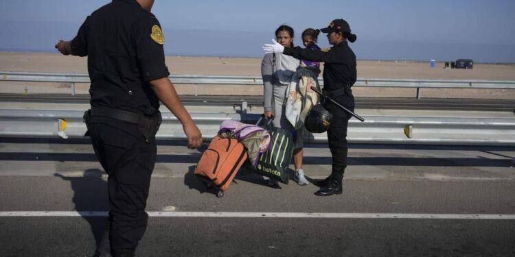 Un migrante venezolano y un niño son detenidos por la policía en Tacna, Perú, el viernes 28 de abril de 2023. (AP Foto/Martín Mejía)